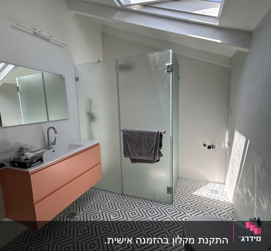 מקלחון זכוכית עם מגבת תלויה על הדלת